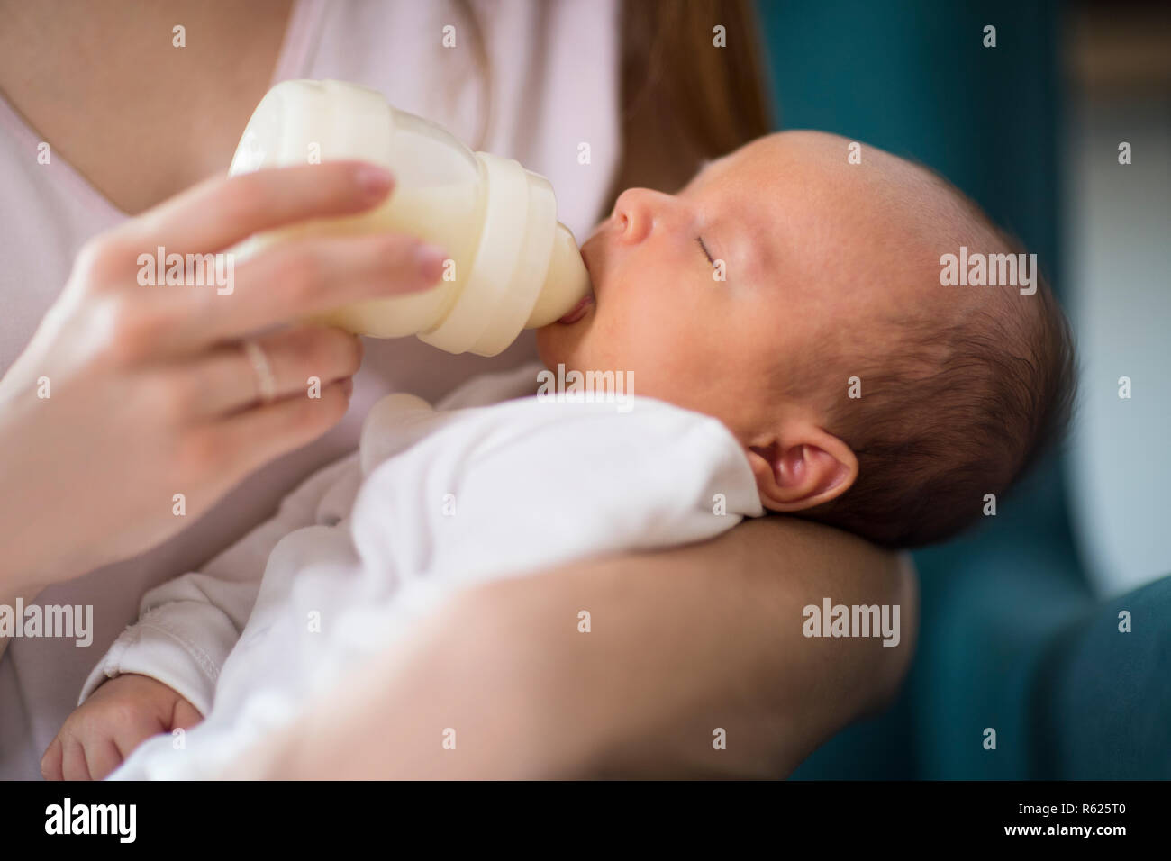 Close Up di Madre amorevole alimentazione neonato Figlio con bottiglia in casa Foto Stock
