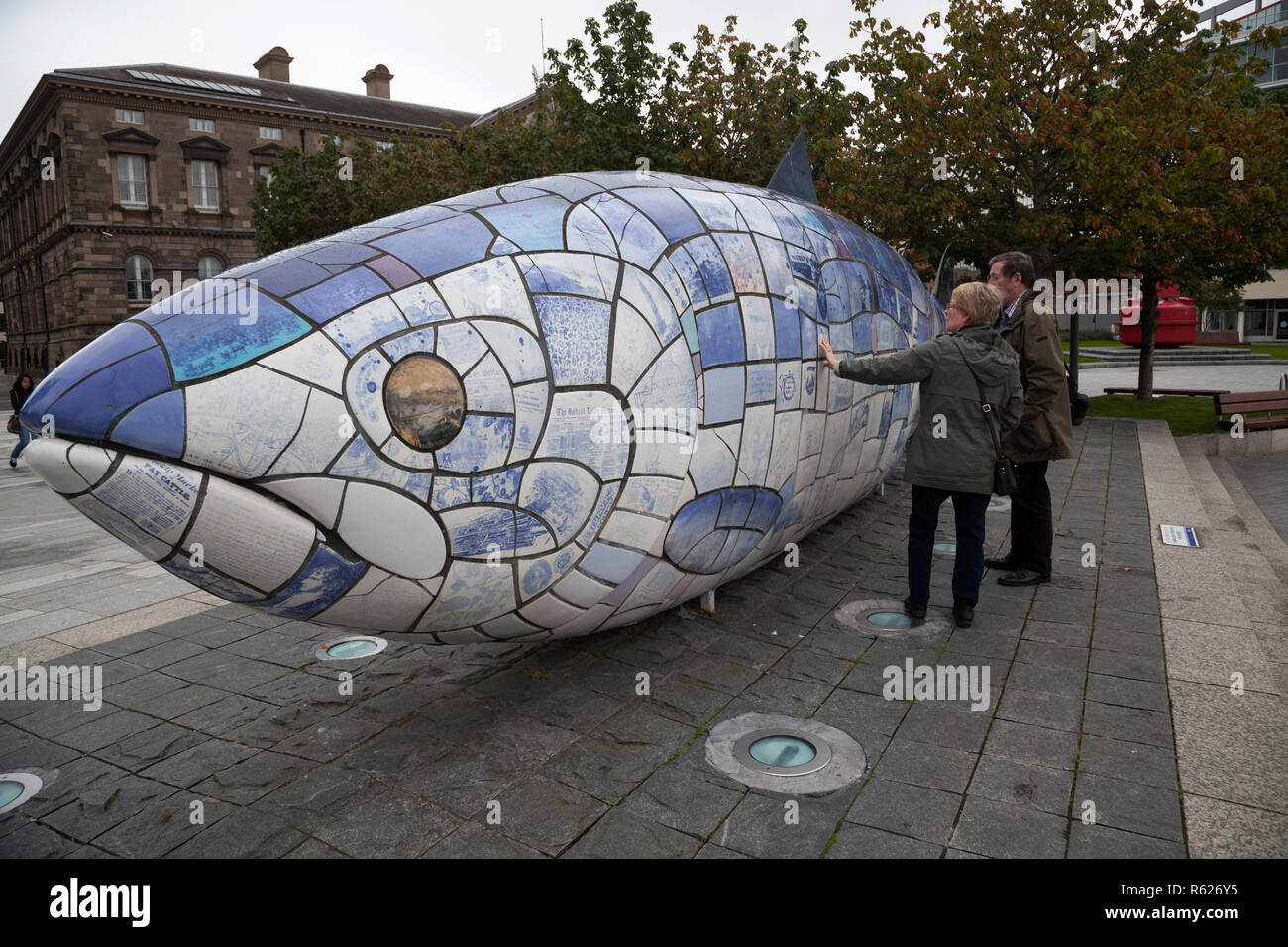 Giovane ammirando la grande scultura di pesce da John gentilezza a Donegall Quay dal fiume Lagan, Belfast, County Antrim, Irlanda del Nord. Foto Stock