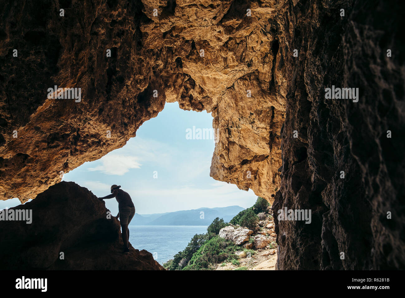 Maschio di rocciatore silhouette su una scogliera in una grotta contro il bellissimo paesaggio marino Foto Stock