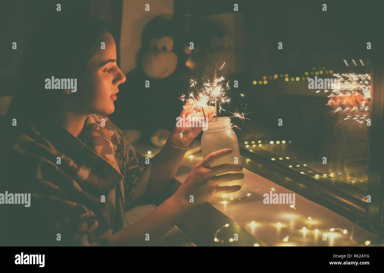 Giovane donna che illumina i fuochi d'artificio a casa Foto Stock