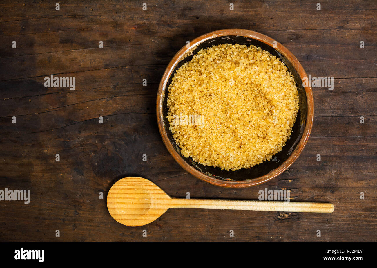 Zucchero di canna in una ciotola su una tavola di legno vista superiore Foto Stock