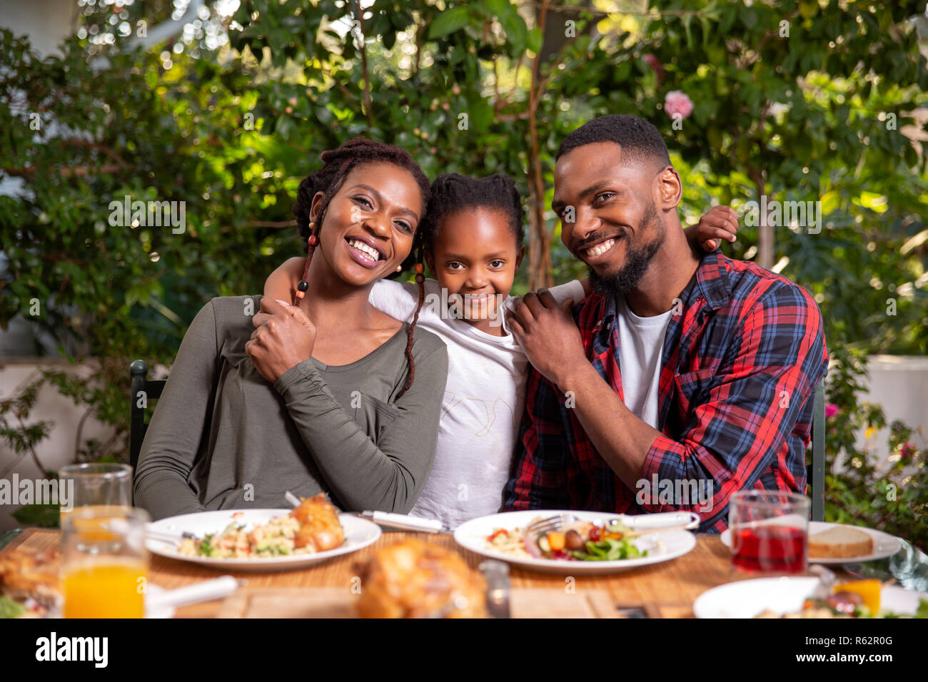 I genitori e la loro figlia seduti ad un tavolo pranzo Foto Stock