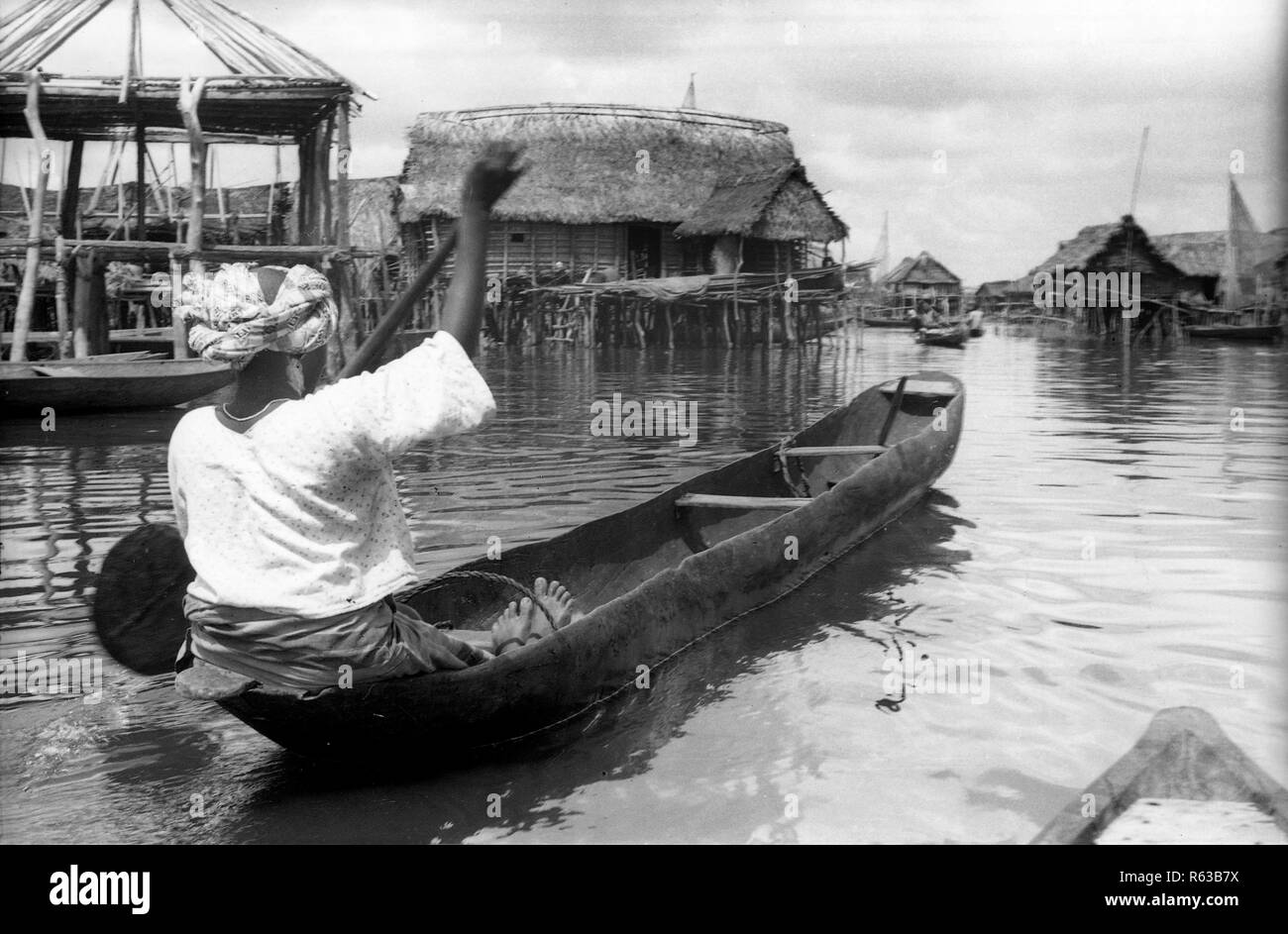 Donna paddling una canoa nel villaggio galleggiante di Makoko in Nigeria Africa 1959 Foto Stock