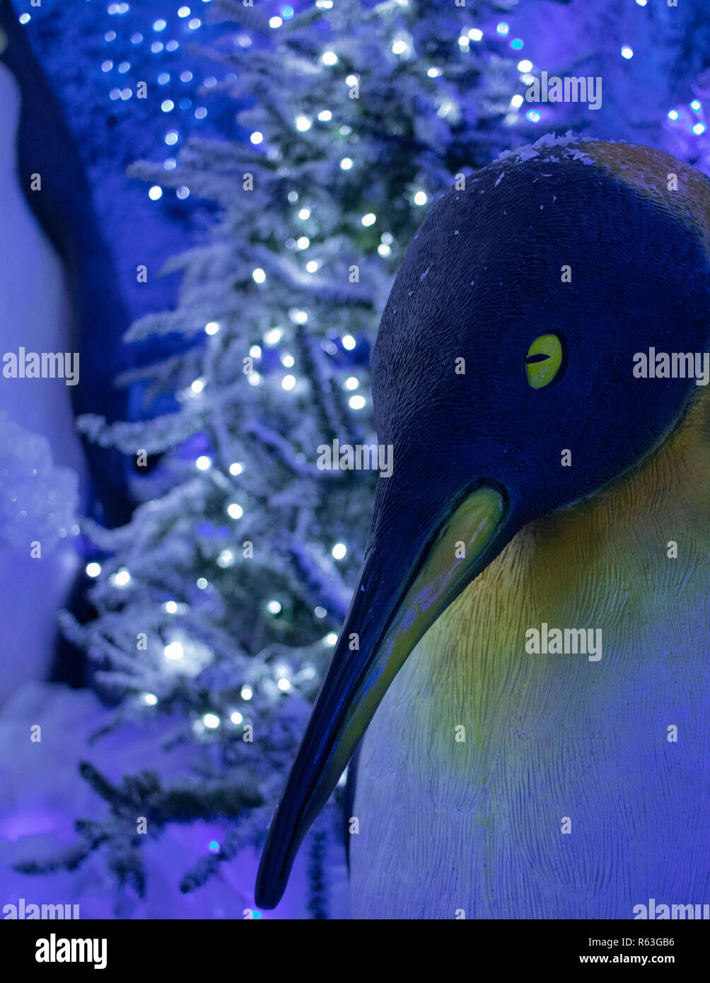 Pinguino imperatore statua di Natale con albero di Natale e le luci di Natale in background Foto Stock
