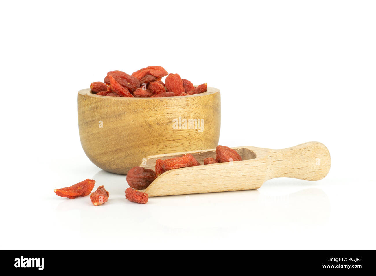 Sacco di essiccato intero red goji bacche di uno scoop con ciotola di legno isolato su sfondo bianco Foto Stock