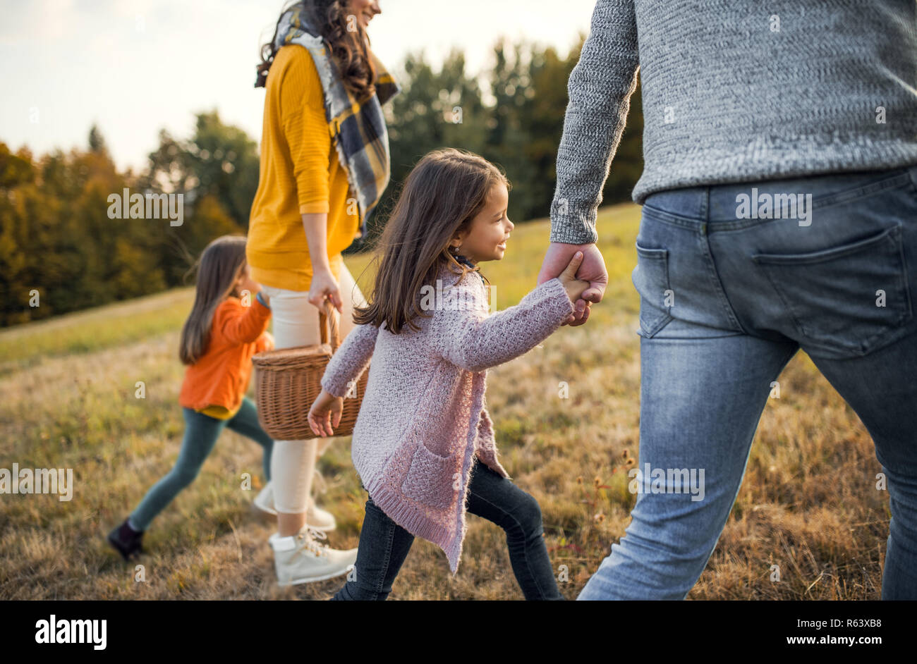 Una sezione mediana della giovane famiglia con due bambini piccoli a camminare in autunno la natura. Foto Stock