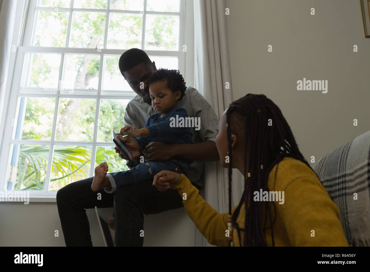 La famiglia tramite telefono cellulare in un salotto Foto Stock