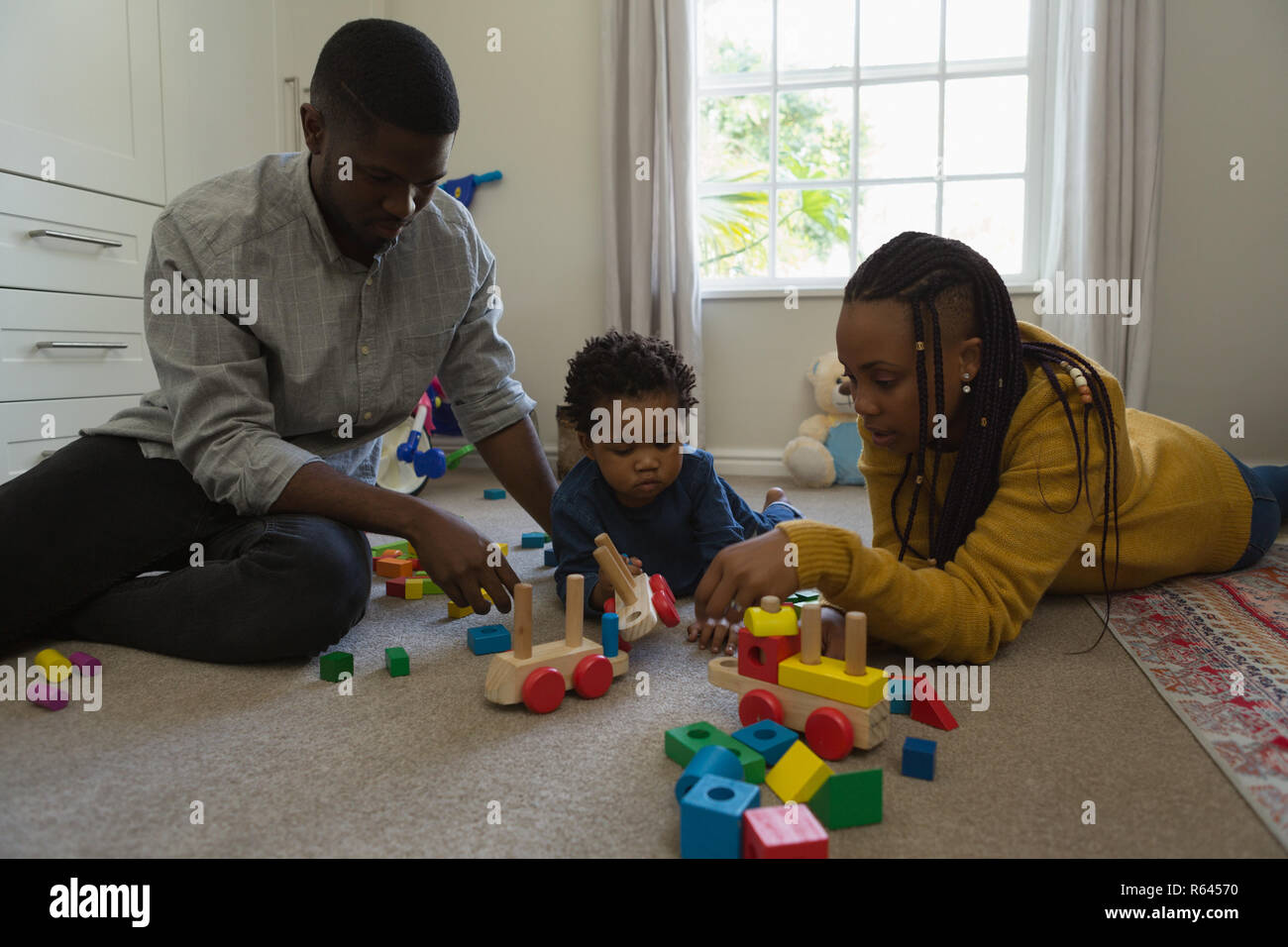 La famiglia gioca con un bambino in una stanza vivente Foto Stock