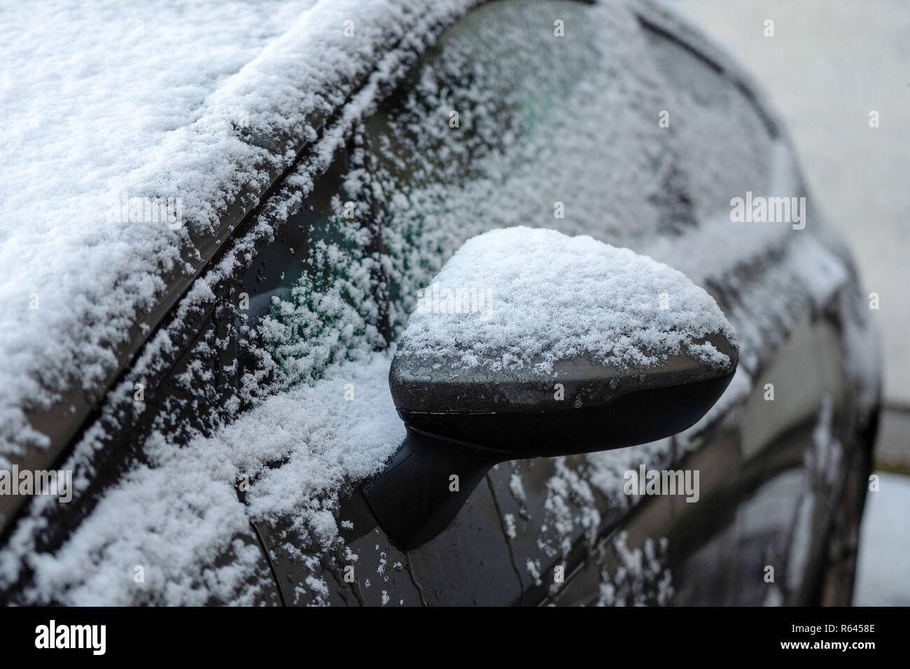 Close-up di coperta di neve auto specchio di ala. Foto Stock