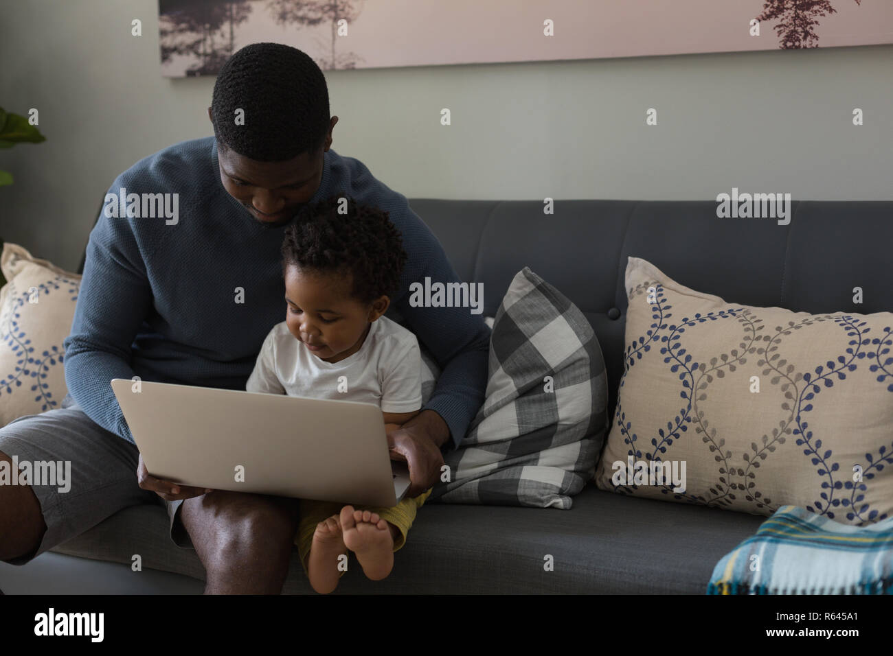 Padre e figlio utilizzando computer portatile in una stanza vivente Foto Stock