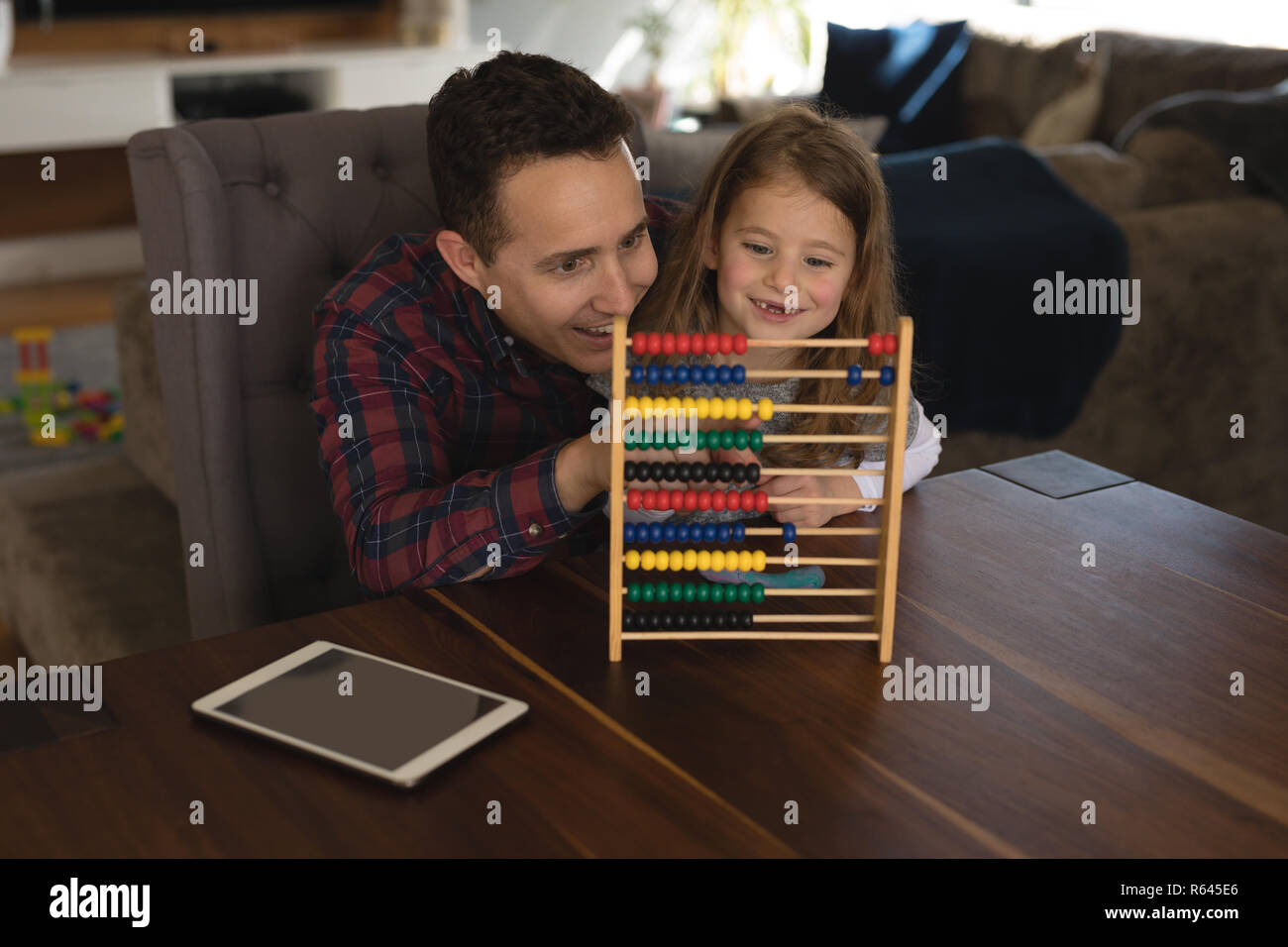 Padre giocando abacus con sua figlia in salotto Foto Stock