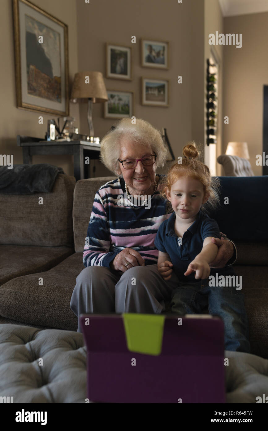 Nonna e nipote rendendo la chiamata video su tavoletta digitale in salotto Foto Stock
