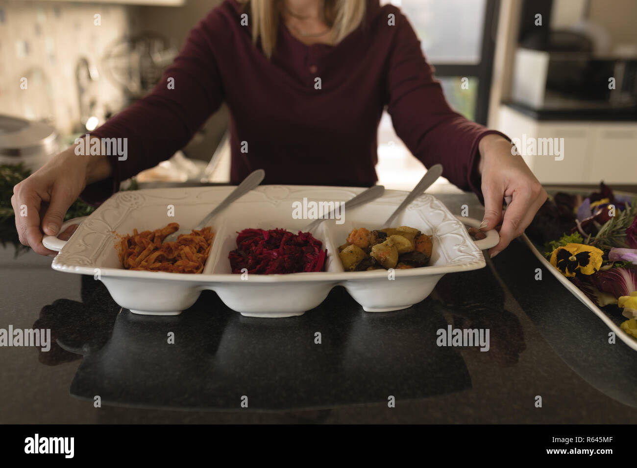 Donna che mantiene il vassoio per alimenti in cucina a casa Foto Stock