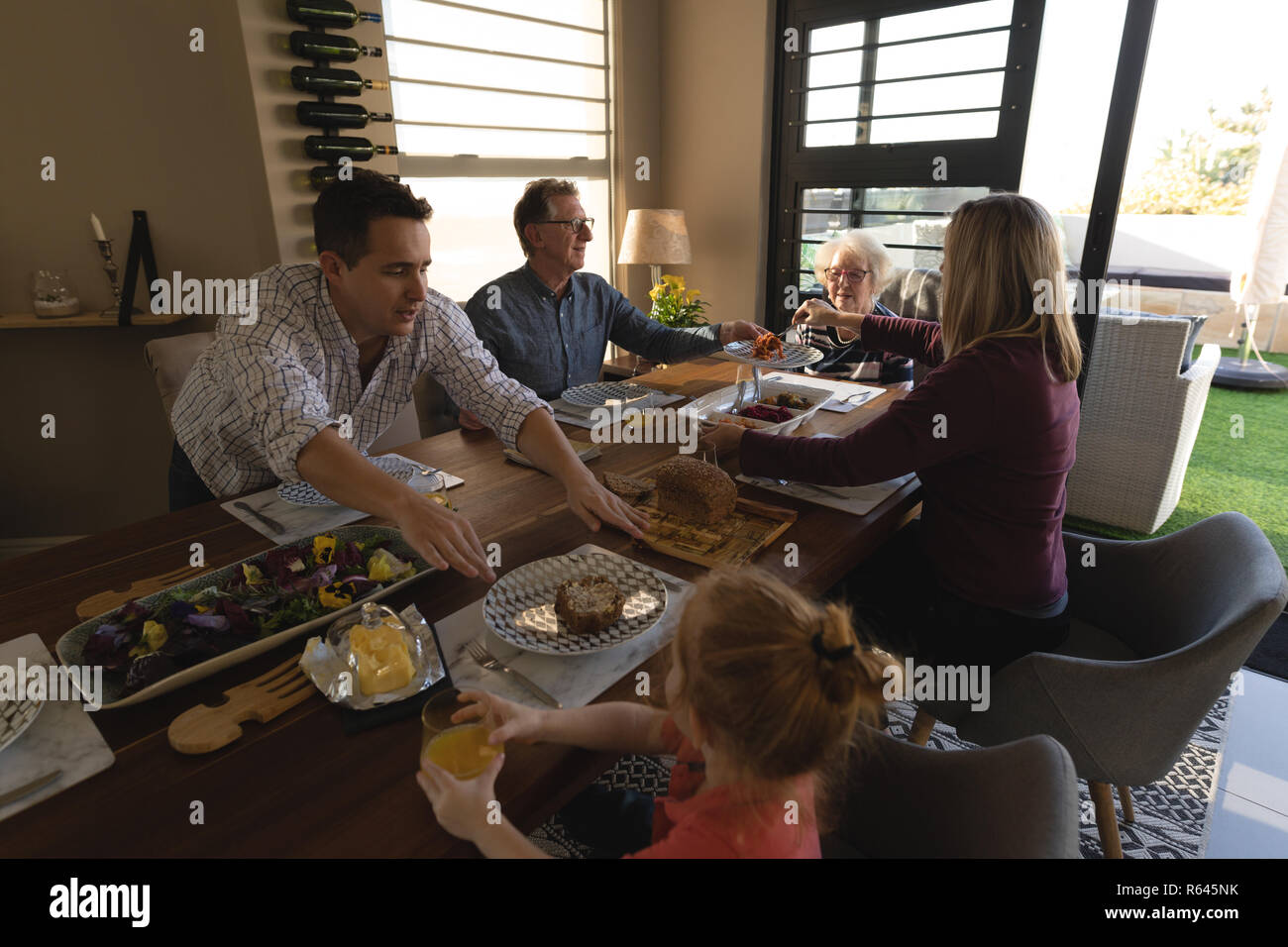 Famiglia avente il cibo sul tavolo da pranzo in soggiorno Foto Stock