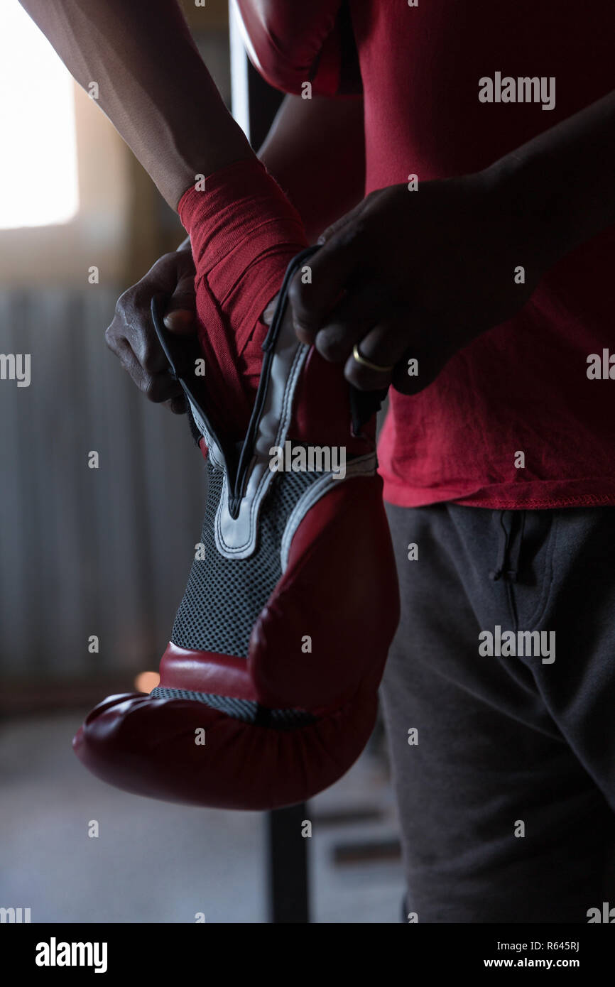Trainer aiutando boxer maschio in indossando guanti di inscatolamento Foto Stock