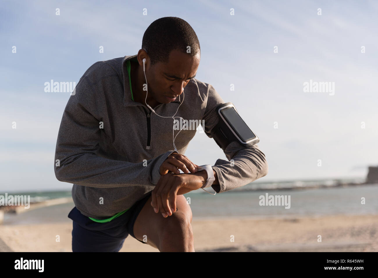 Atleta maschio nel controllo della sua smartwatch durante l'esercizio Foto Stock