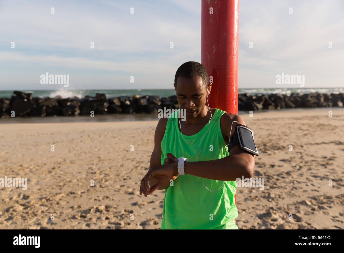 Atleta maschio utilizzando smartwatch vicino alla spiaggia Foto Stock