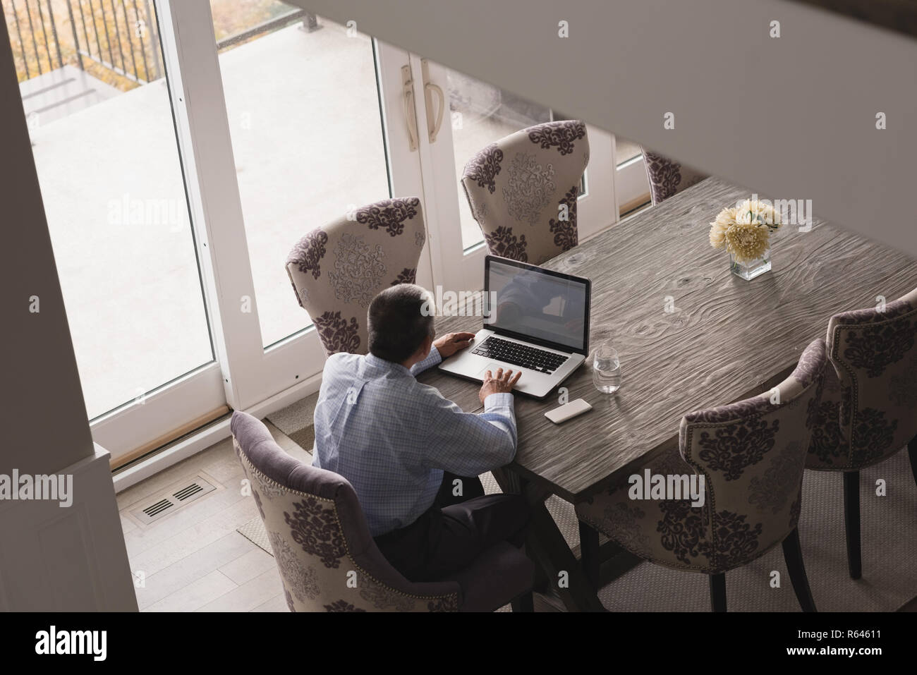Senior uomo utilizzando computer portatile sul tavolo da pranzo a casa Foto Stock