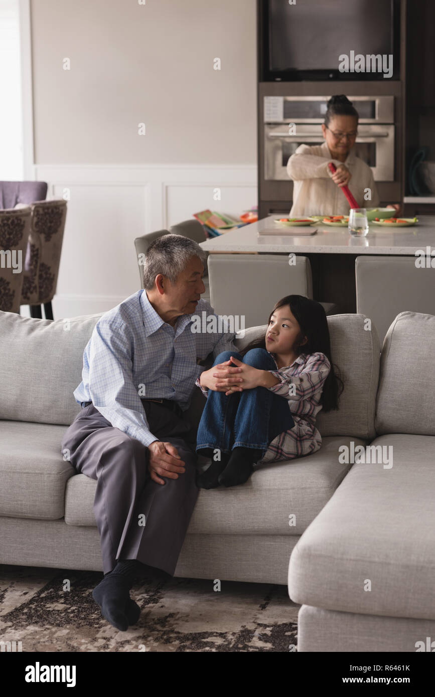 Nonno e nipote che interagiscono con ogni altro sul divano nel soggiorno Foto Stock