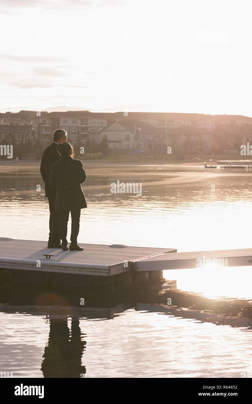 Coppia senior in piedi o molo vicino a lato lago Foto Stock