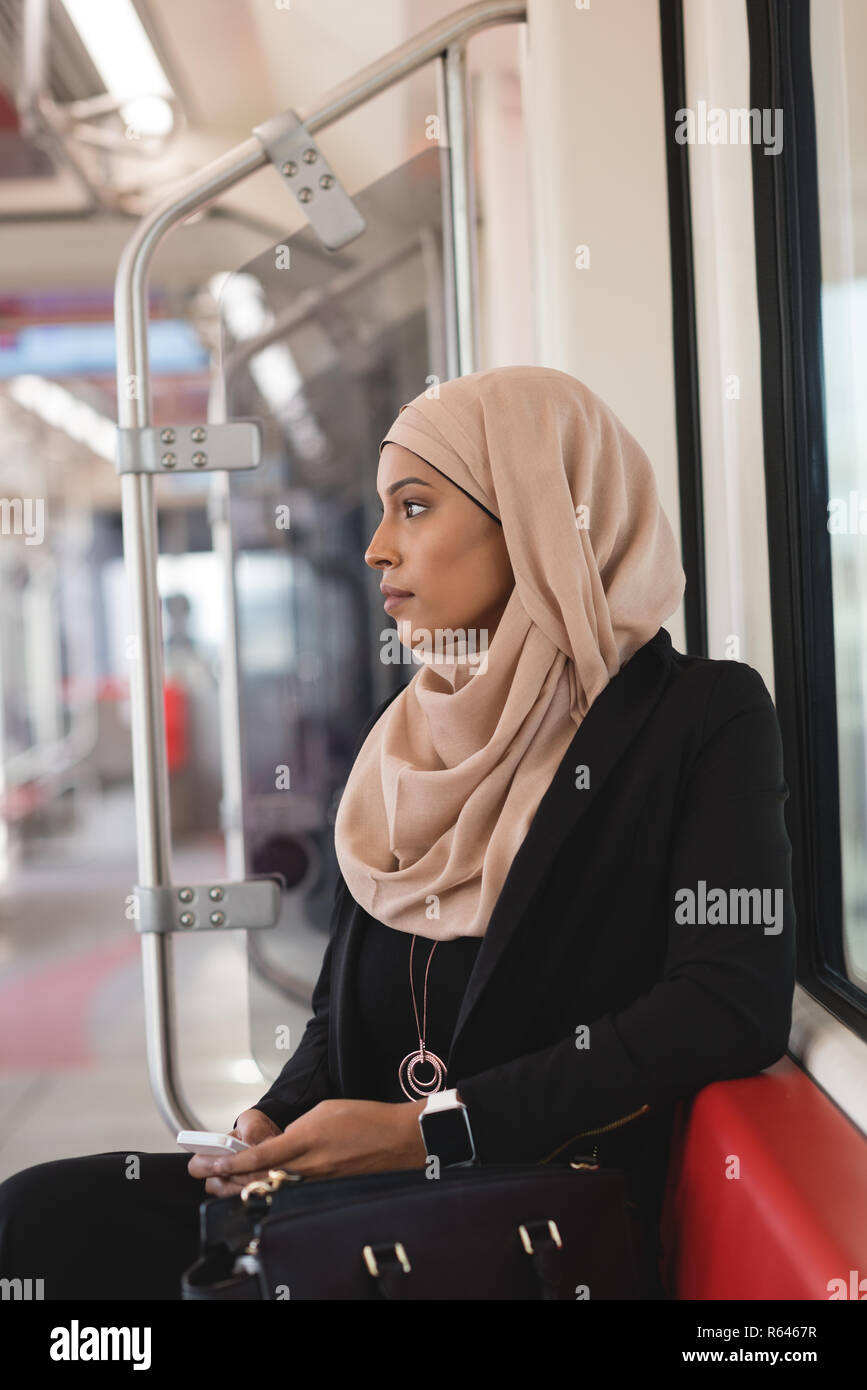 Donna che utilizza il telefono cellulare mentre si è in viaggio in treno Foto Stock