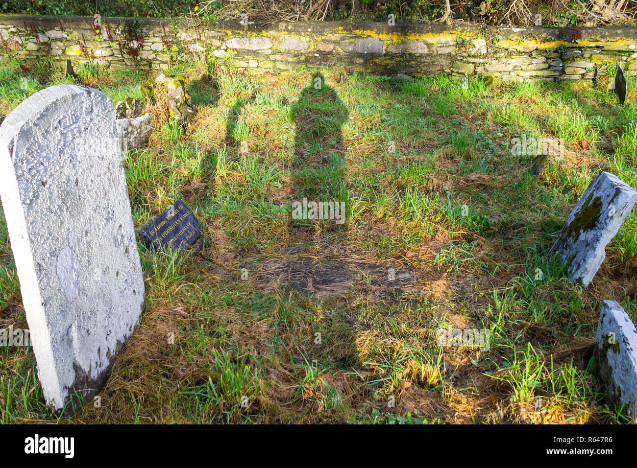 Ombra o silhouette espressi da mattina presto sole attraverso antiche tombe in un cimitero Foto Stock