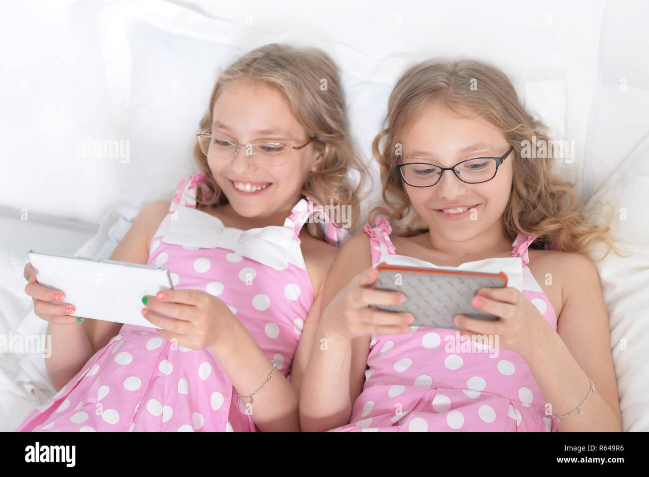 Ritratto di due sorelle gemelle utilizzando gli smartphone Foto Stock
