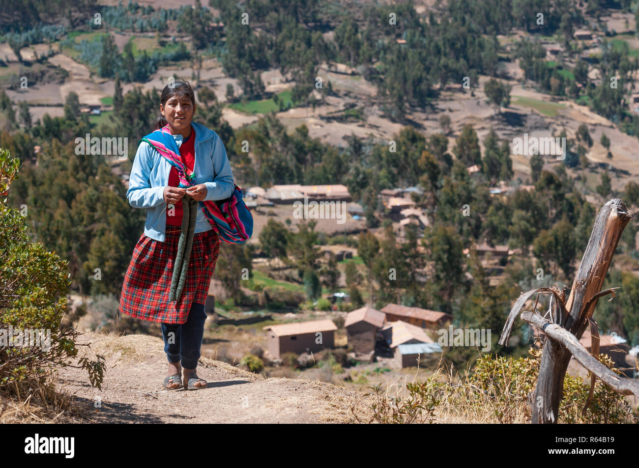 Pisac, Perù - 8 Agosto 2011: una ragazza locale a piedi e la sua città. Foto Stock