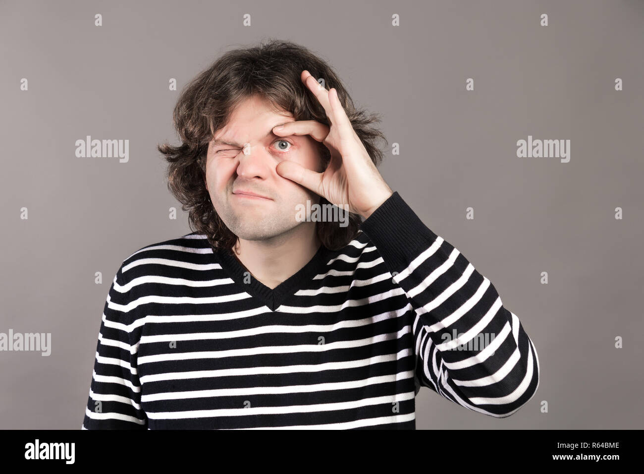 Un uomo di allargare il suo occhio con pollice e indice. Stanco guy aprire il suo occhio ampiamente con le dita, avente il rossore interno a causa della privazione del sonno, mostra Foto Stock