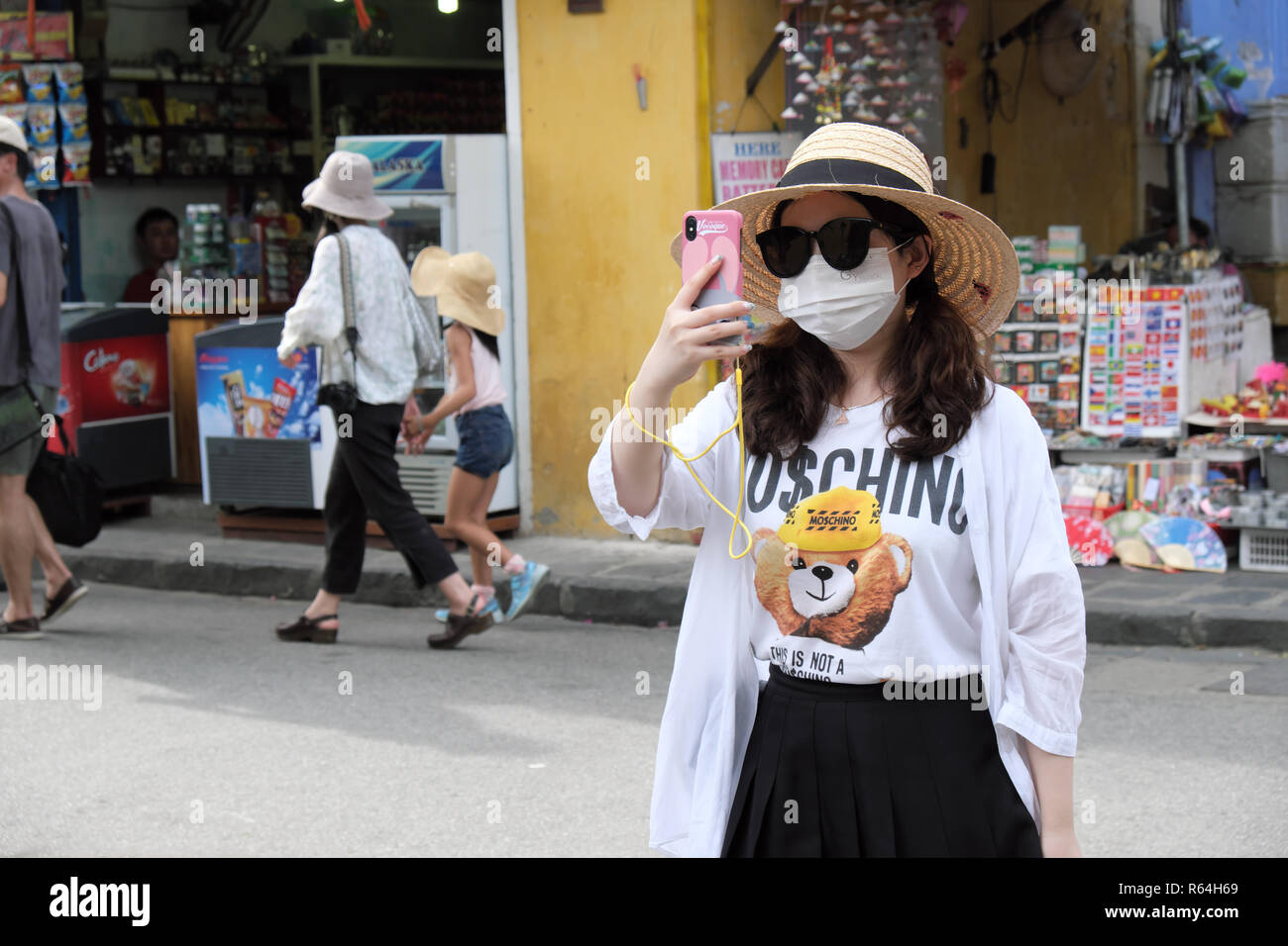 Hoi An Vietnam - Un turista asiatico che indossa una maschera facciale prende un selfie foto sul suo telefono nella vecchia città di Hoi An nel 2018 Foto Stock