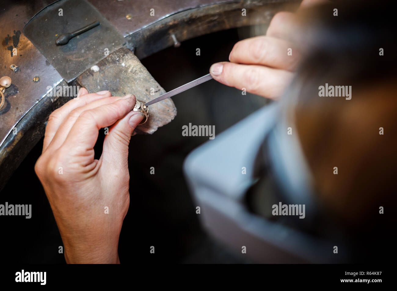 Gioielliere lavorando con un ago file un anello d'oro su un vecchio banco in autentici gioielli workshop Foto Stock