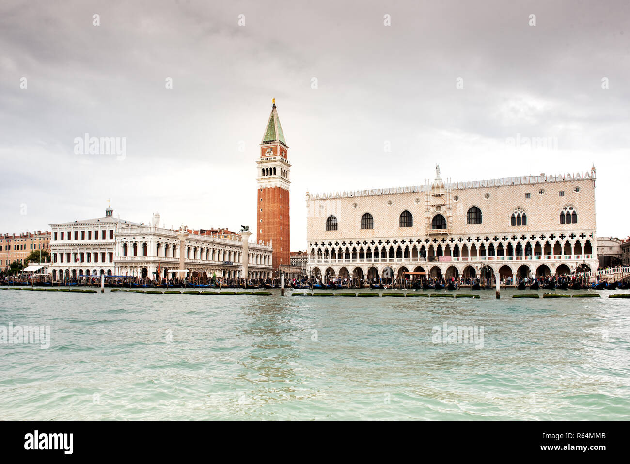 Piazza San Marco vista dall'acqua del Canal Grande, con la torre in centro, dal basso angolo contro nuvoloso cielo grigio. Venezia, Italia Foto Stock