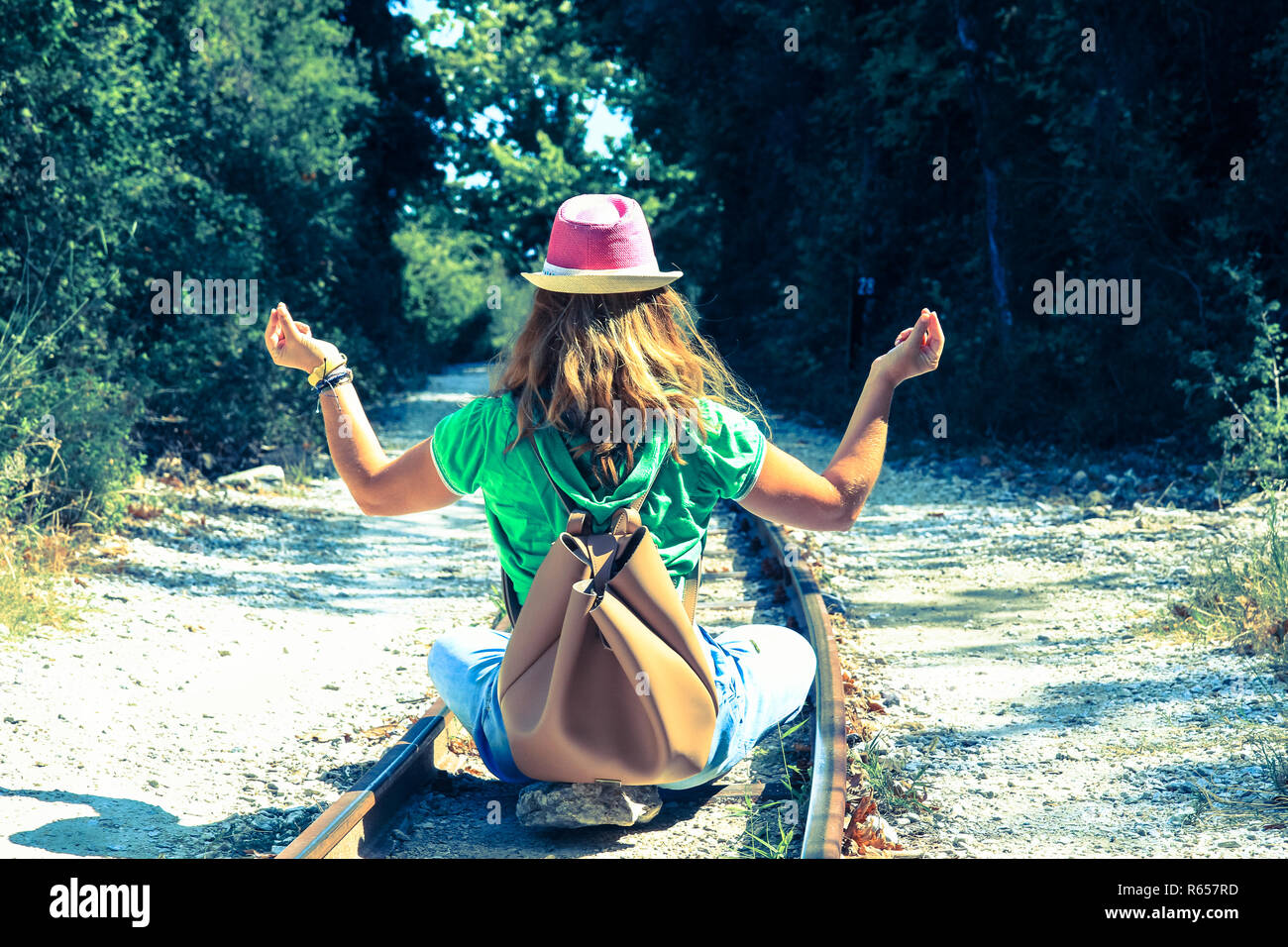 Una donna seduta con la schiena girata su binari e la pratica dello yoga. Foto Stock