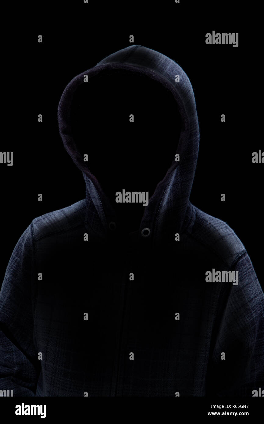 Un anonimo backlit misterioso uomo felpa con cappuccio da indossare in silhouette isolati su sfondo nero. Concetto di un criminale o spooky male stalking nelle sh Foto Stock