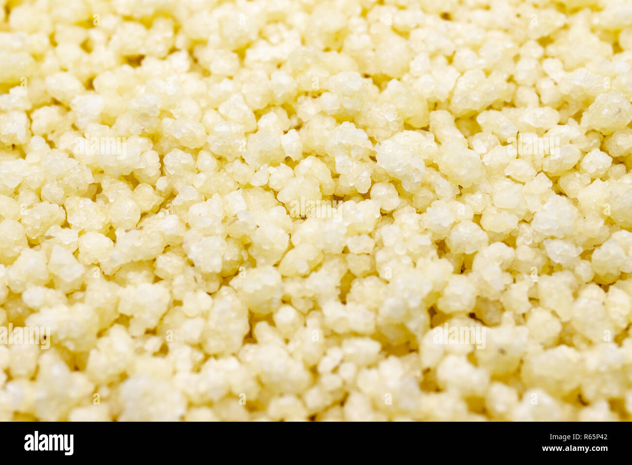 Il cous cous macro. Piccole sfere al vapore di frantumato di semola di grano duro. Foto Stock