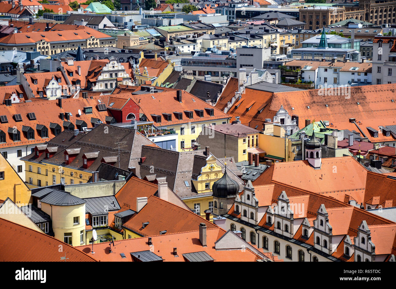 Urbana densa cityscape di tetti rossi e i suoi edifici colorati in giallo, bianco e toni di verde nel centro della città di Monaco di Baviera, Germania Foto Stock