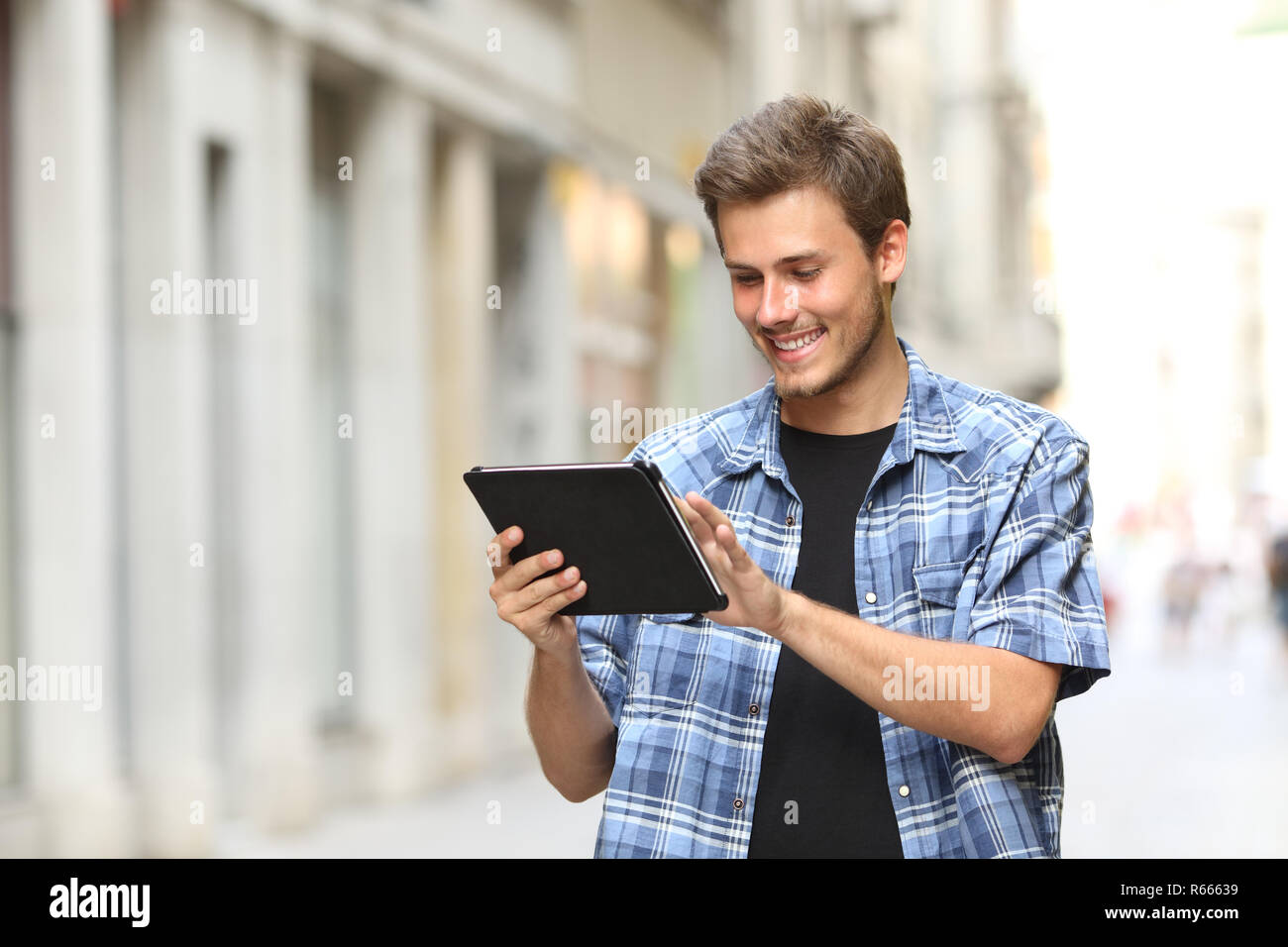 Uomo felice la navigazione a piedi tablet contenuto online in strada Foto Stock