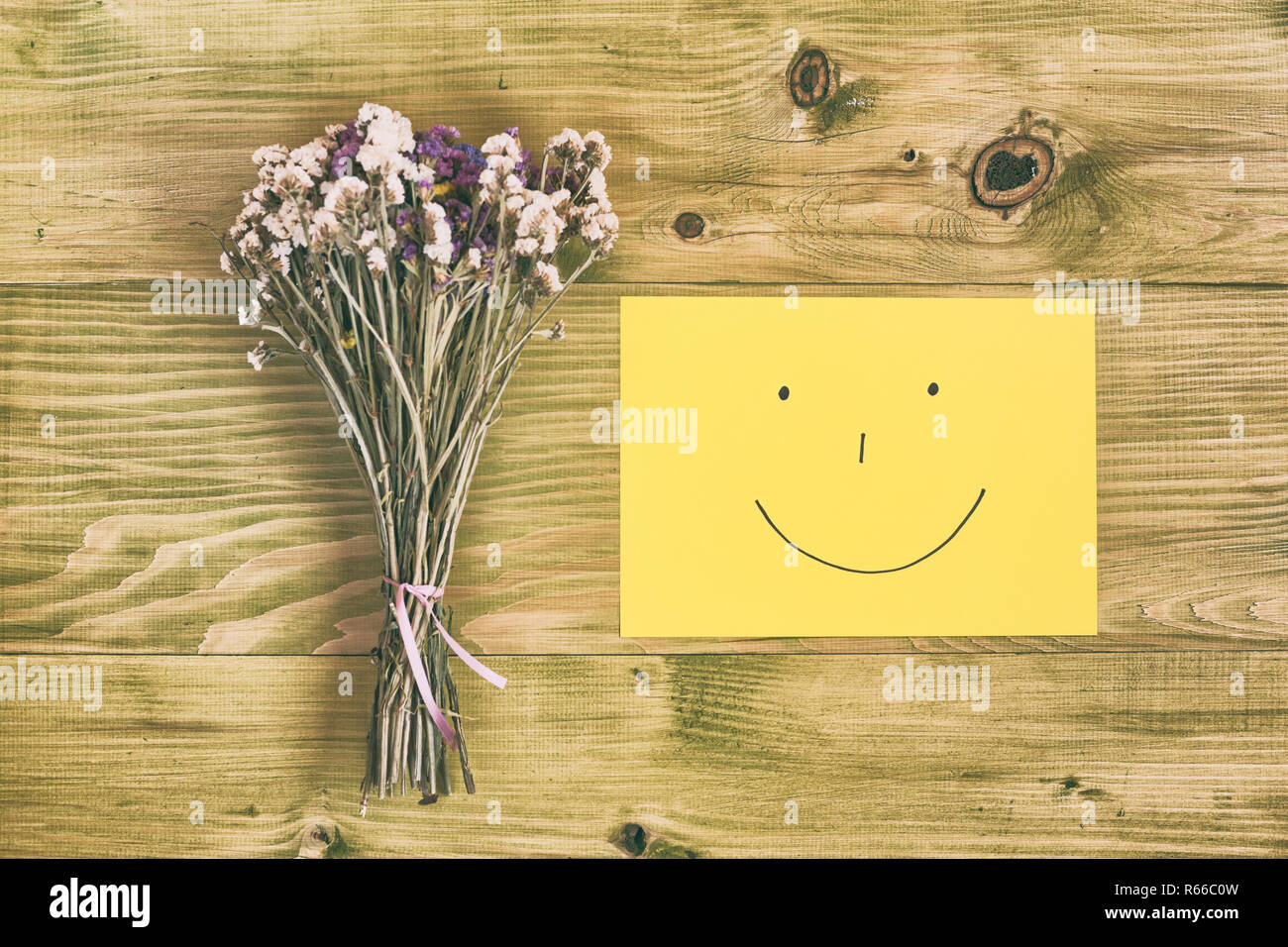 Bouquet di fiori e Smiley face sul tavolo di legno. Foto Stock