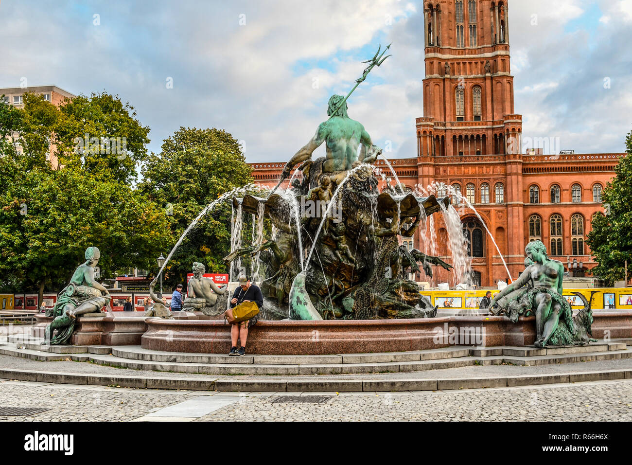 I turisti rilassarsi presso la fontana del Nettuno nel cortile antistante il Rotes Rathaus o Red Town Hall di Alexanderplatz di Berlino, Germania Foto Stock