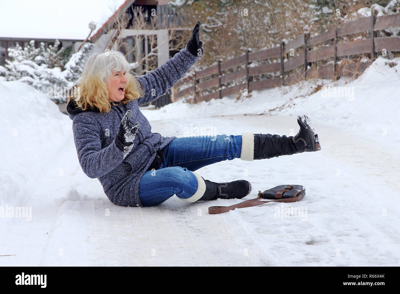 Una donna è scivolato sulla strada invernale e caddero. cadono su una strada uniforme Foto Stock