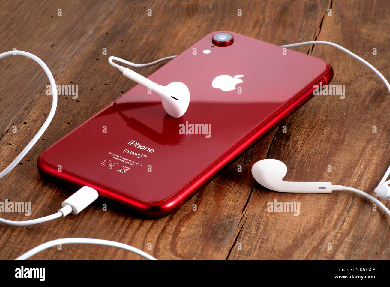 Koszalin, Polonia - Dicembre 04, 2018: Rosso iPhone XR su un tavolo di legno con gli auricolari bianchi. L'iPhone XR è smart phone con multi touch screen produ Foto Stock