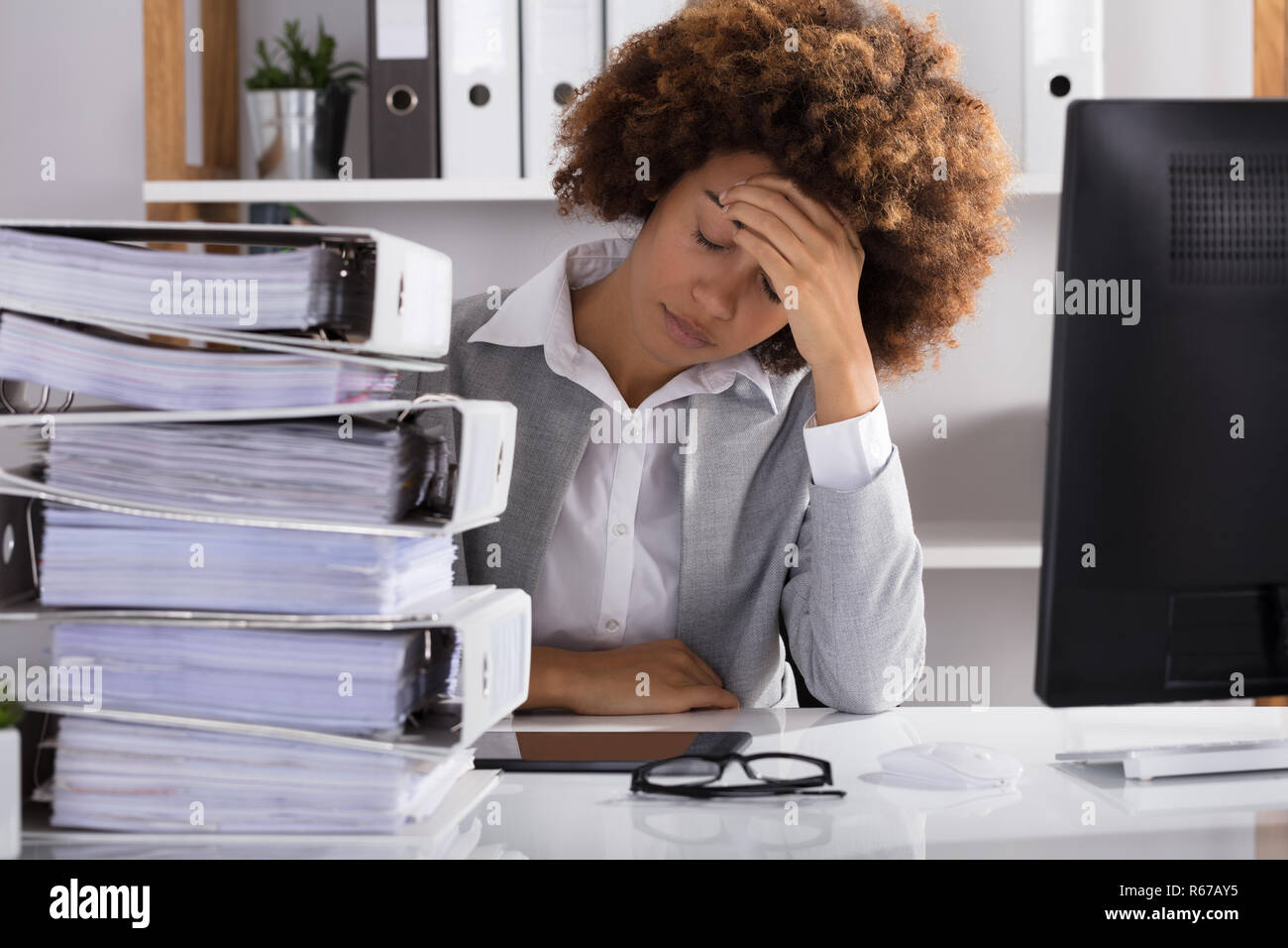 Stressante imprenditrice seduta in ufficio Foto Stock