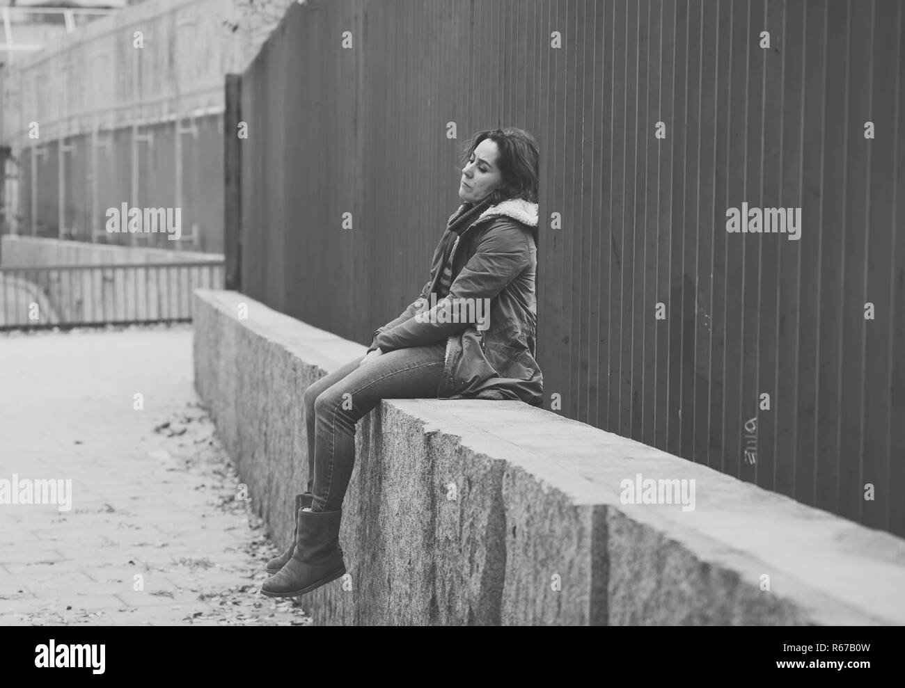 Donna attraente affetti da depressione abbattimento triste infelice heartbroken e solitaria seduta in città strada urbana in salute mentale dolore emotivo Abu Foto Stock