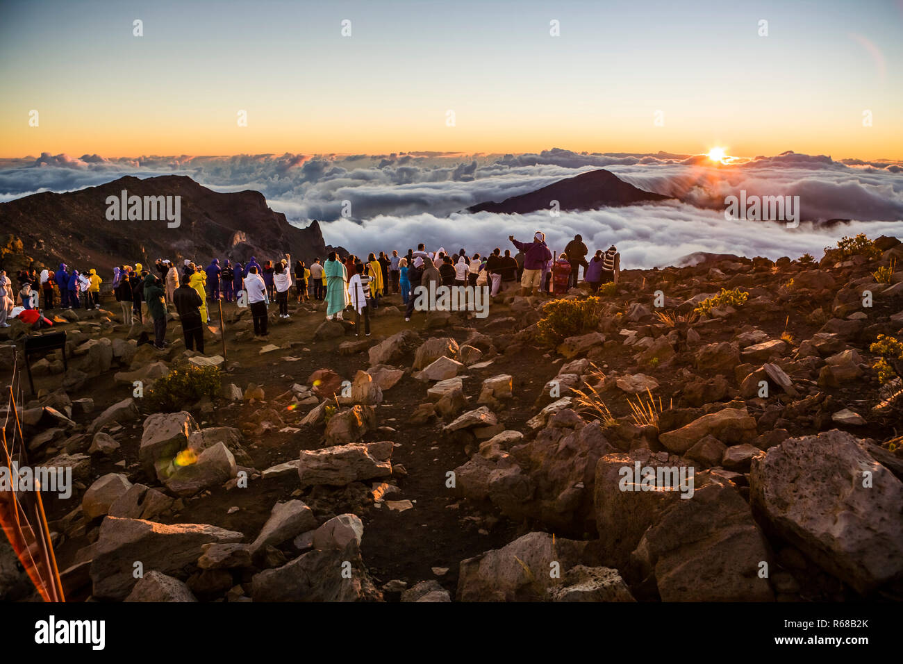 Un grande gruppo di persone a guardare il sole sorgere sulla cima del Vulcano Haleakala a Maui, Hawaii Foto Stock