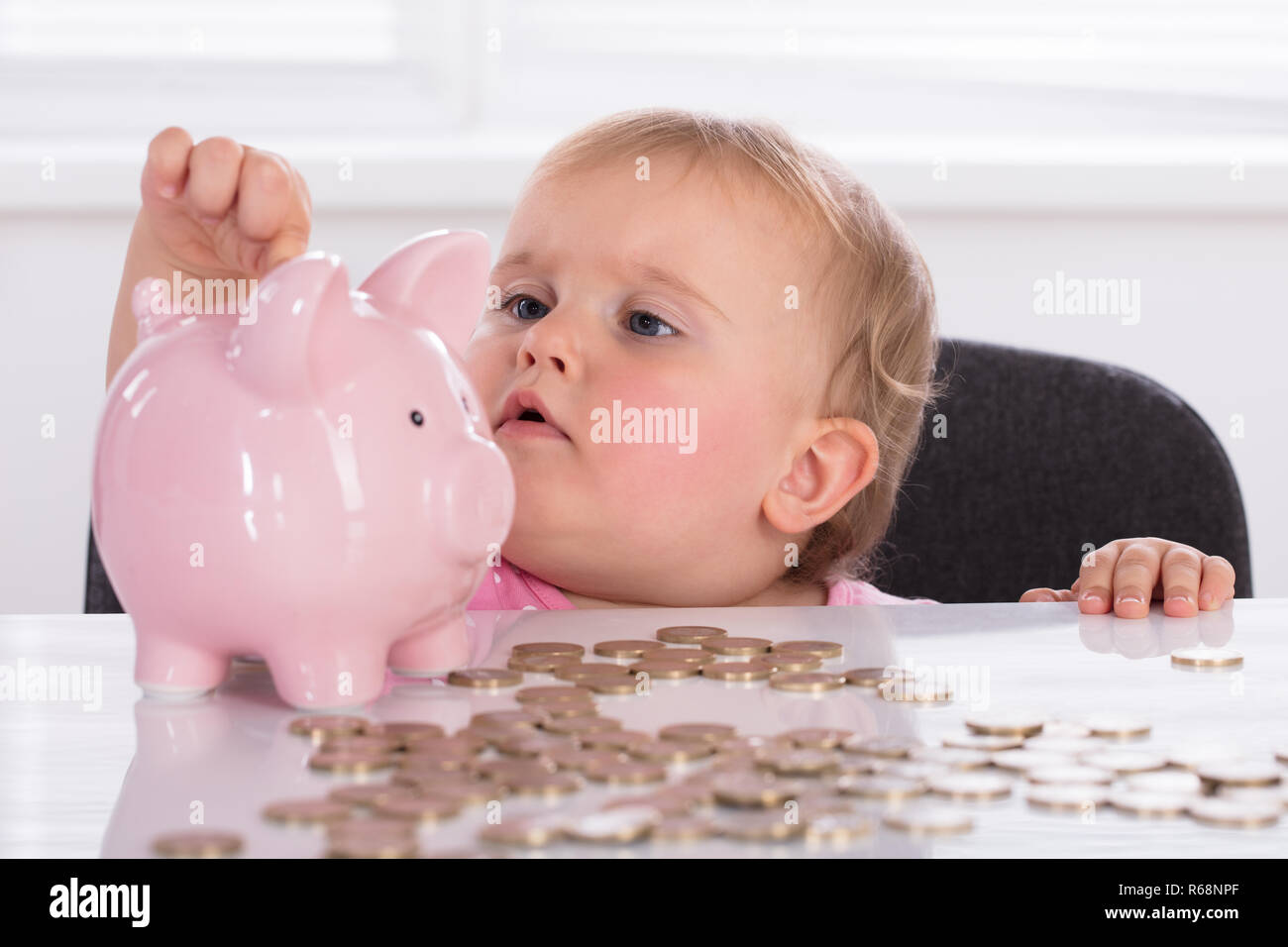 Baby inserimento di moneta in Piggybank Foto Stock
