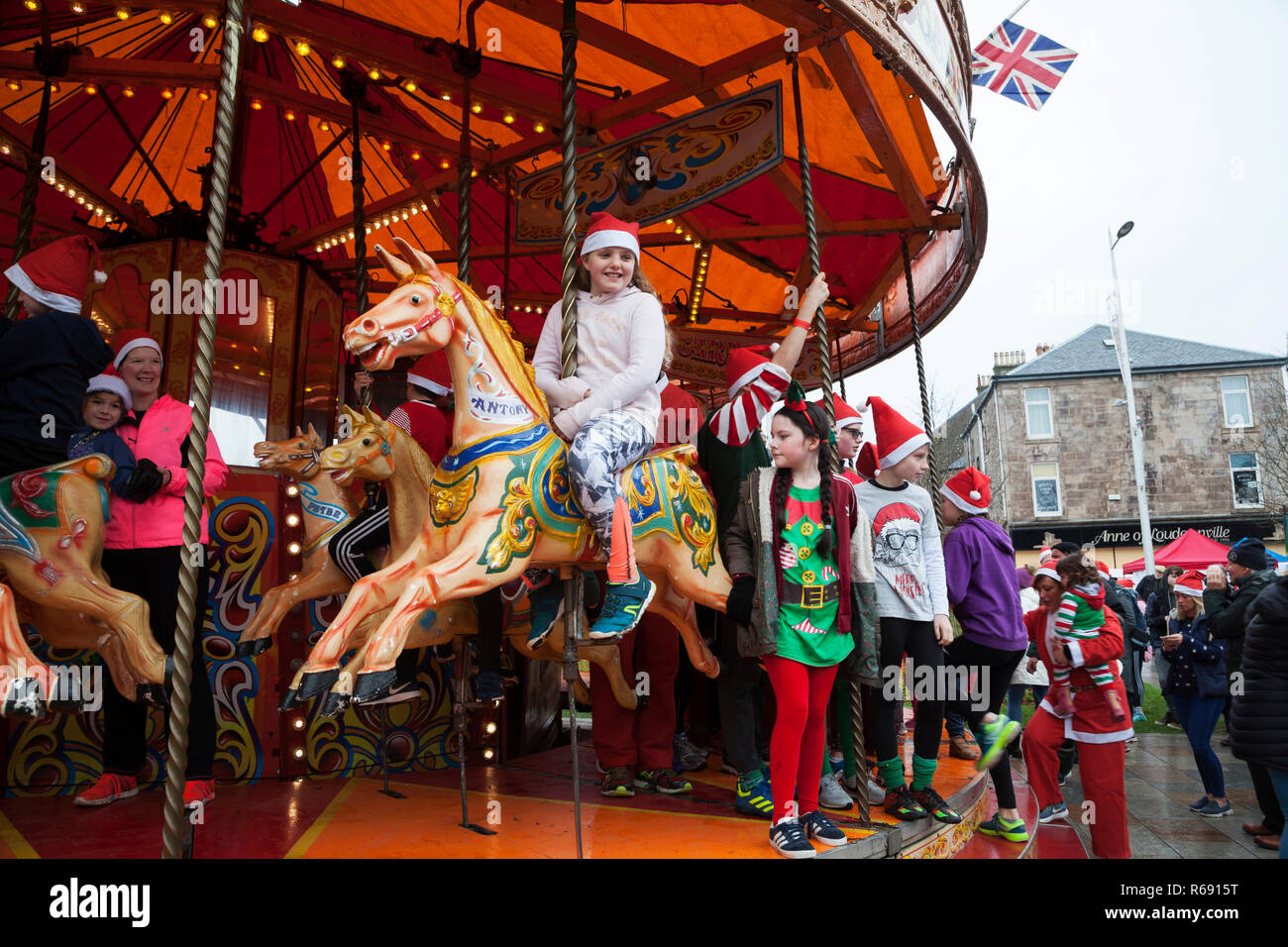 Giostra cavallo Merry Go Round con cavalli al galoppo e bambini al parco di divertimenti al Festival Invernale, Helensburgh, Argyll, Scozia Foto Stock