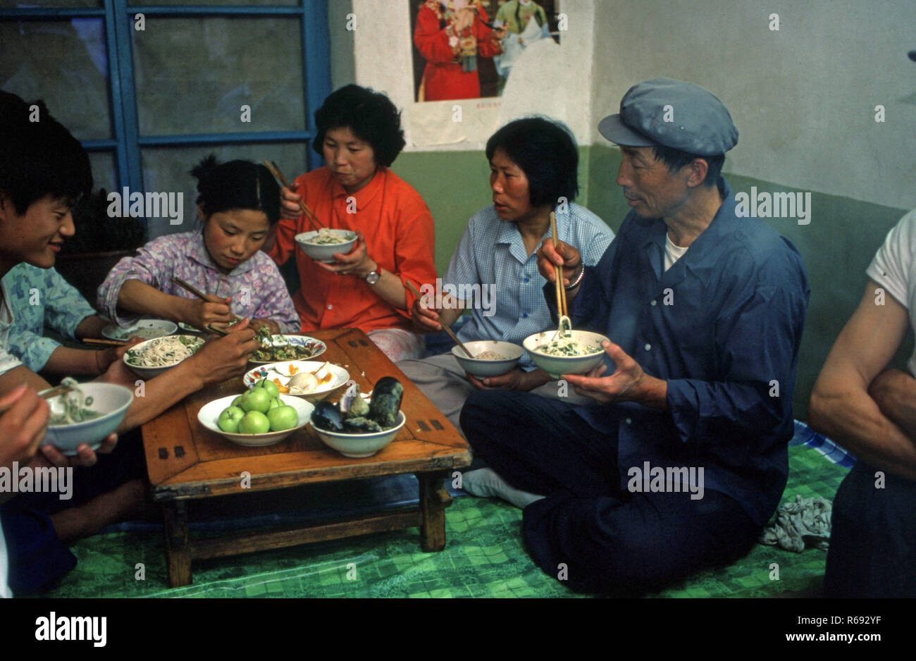 Cina settentrionale 1980 Comune in provincia Waoning in un interno di una casa in cui una famiglia sono di mangiare un pasto seduti su un kang un letto stufa che è una piattaforma di mattoni dove incanalata aria viene alimentata da un incendio fornendo calore, solitamente a fuoco di legno. Foto Stock