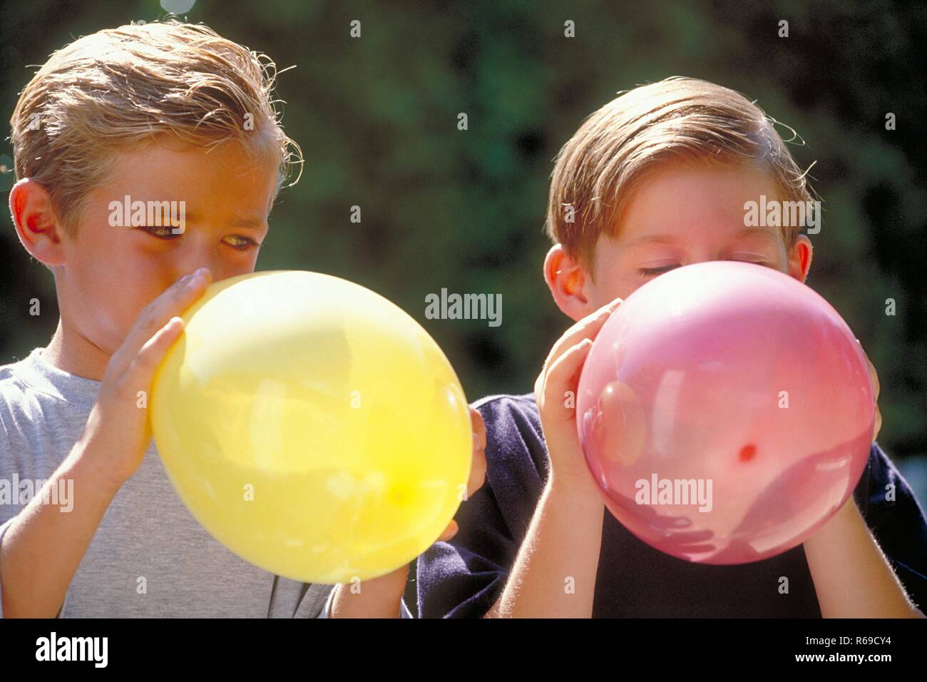 Ritratto, all'aperto, zwei Jungen bionda, 6-8 Jahre alt, blasen bunte Luftballons auf Foto Stock
