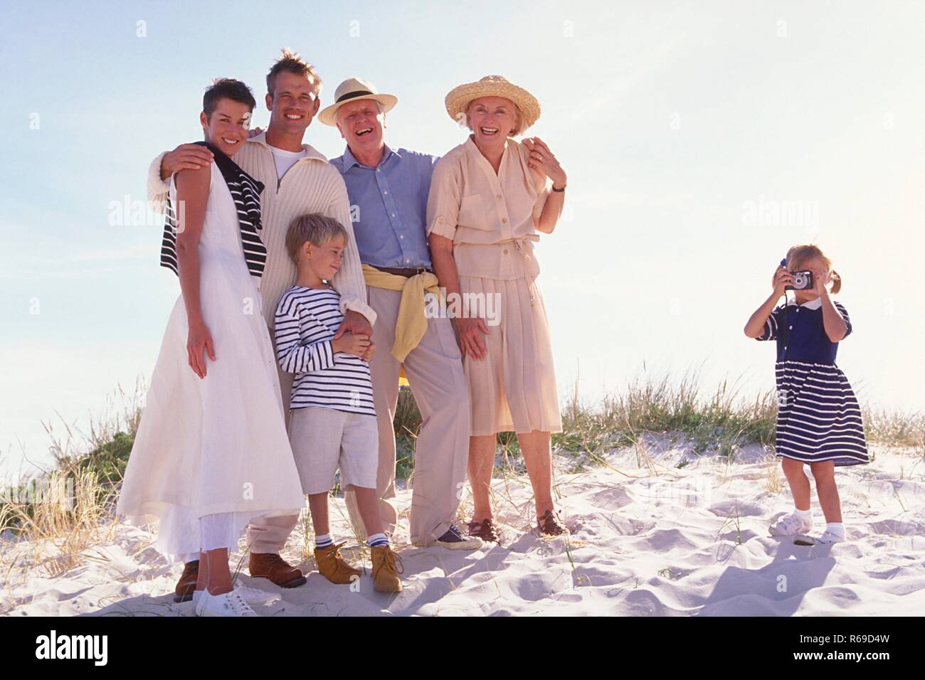 Strandszene, bionde Maedchen macht am Strand ein Gruppenfoto von ihrer Familie mit den Eltern, Grosseltern und ihrem Bruder Foto Stock