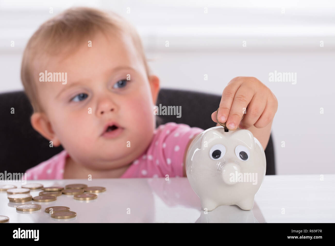 Baby inserimento di moneta in Piggybank Foto Stock